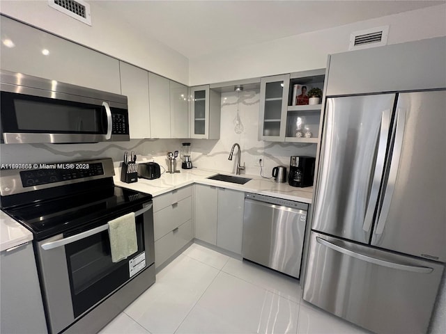 kitchen featuring gray cabinetry, sink, light tile patterned flooring, and stainless steel appliances