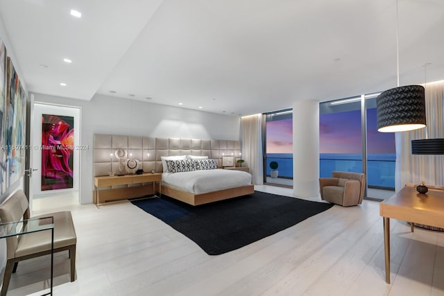 bedroom with hardwood / wood-style flooring and a water view