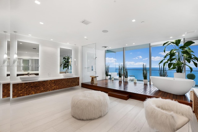 interior space with vanity, expansive windows, a water view, and wood-type flooring