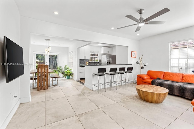 living room featuring light tile patterned floors, ceiling fan, and a healthy amount of sunlight