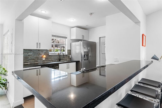 kitchen with sink, stainless steel appliances, backsplash, kitchen peninsula, and white cabinets