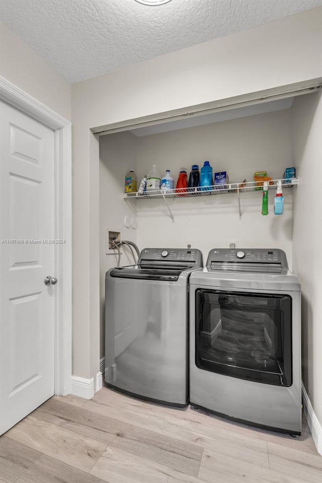 clothes washing area with a textured ceiling, light wood-type flooring, and independent washer and dryer