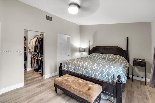 bedroom with a closet, ceiling fan, light wood-type flooring, and a spacious closet