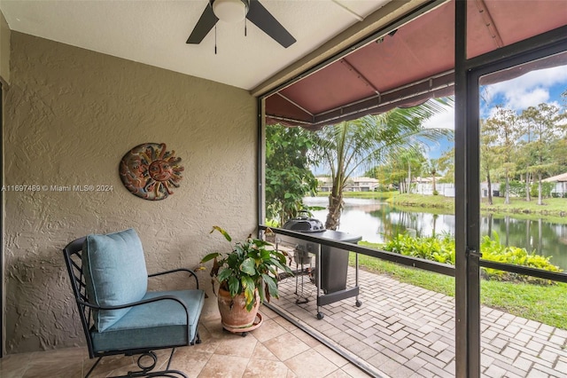 sunroom with ceiling fan and a water view