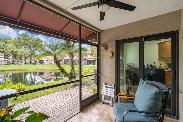 sunroom / solarium with ceiling fan and a water view