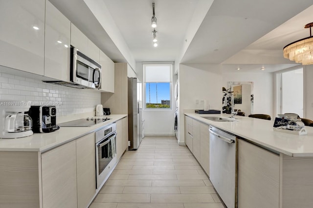 kitchen featuring sink, stainless steel appliances, kitchen peninsula, decorative backsplash, and white cabinets