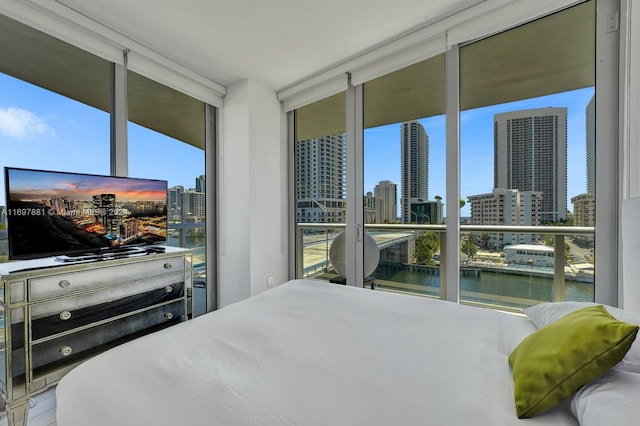 bedroom with a water view and a wall of windows