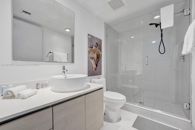 bathroom with tile patterned floors, vanity, toilet, and a shower with door