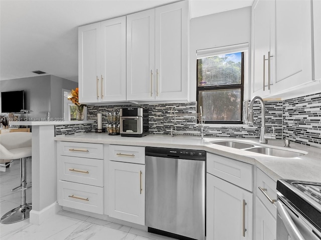 kitchen with white cabinets, a sink, light countertops, stainless steel appliances, and backsplash