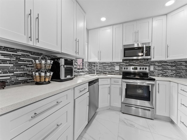 kitchen with tasteful backsplash, light stone counters, stainless steel appliances, sink, and white cabinetry