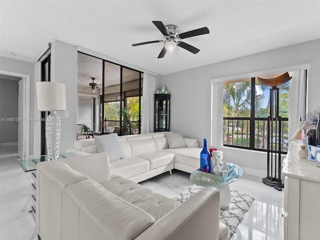 living room featuring a ceiling fan, a wealth of natural light, and marble finish floor