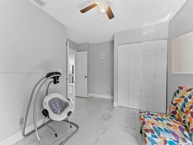 interior space with visible vents, a ceiling fan, a textured ceiling, and marble finish floor