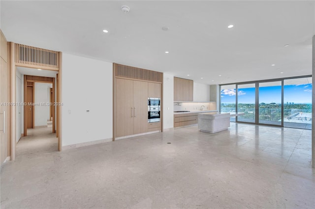 unfurnished living room with floor to ceiling windows and sink