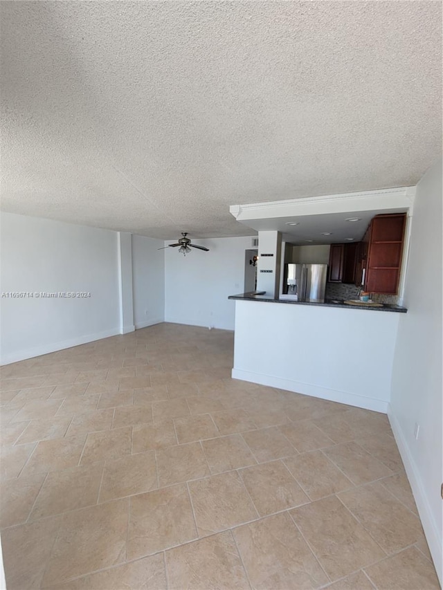 unfurnished living room with a textured ceiling, baseboards, and ceiling fan