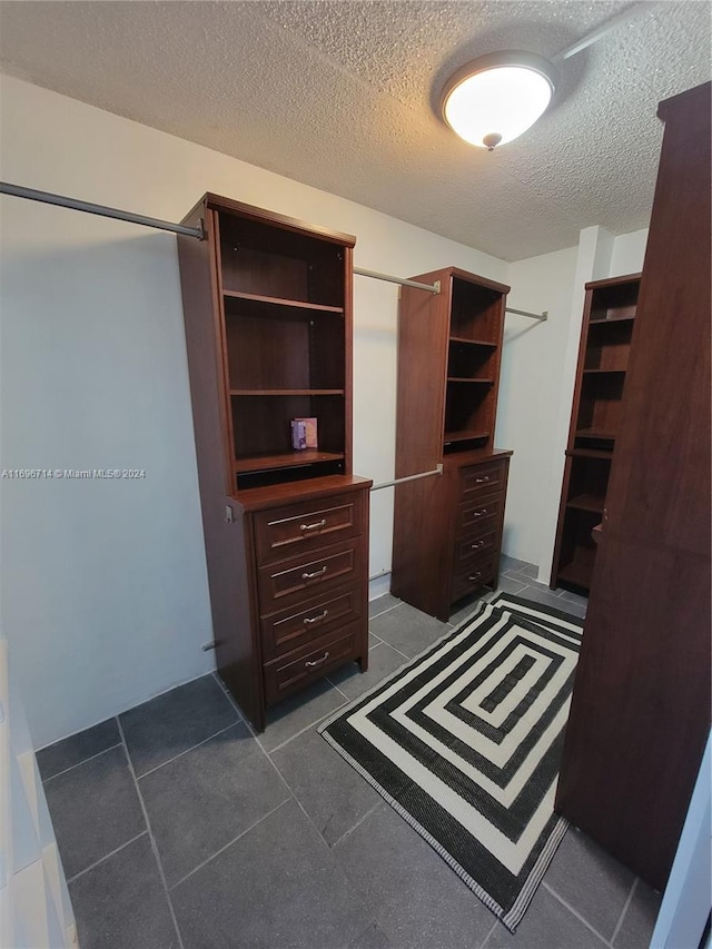 walk in closet with dark tile patterned flooring