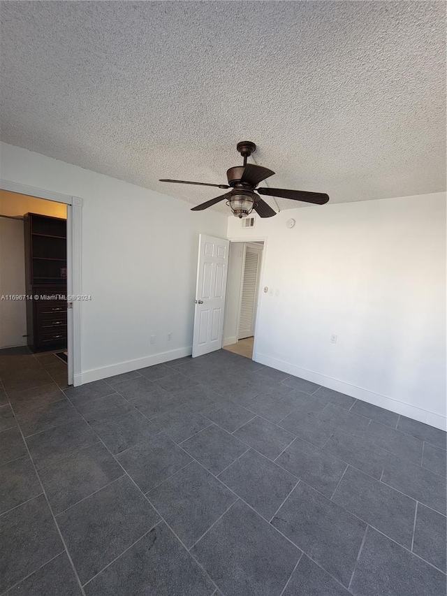 spare room featuring a ceiling fan, baseboards, and a textured ceiling