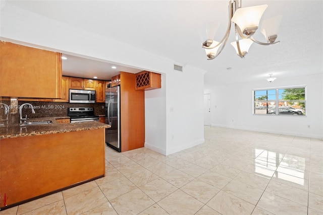 kitchen featuring sink, stainless steel appliances, an inviting chandelier, backsplash, and dark stone counters