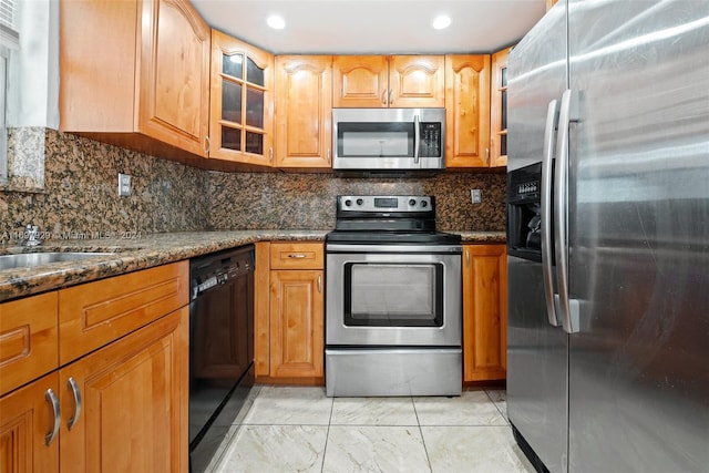 kitchen featuring tasteful backsplash, dark stone counters, and appliances with stainless steel finishes