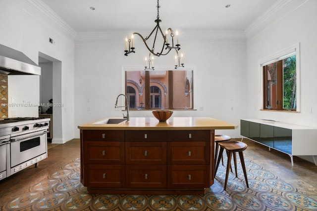 kitchen featuring sink, stainless steel range, an island with sink, pendant lighting, and ornamental molding