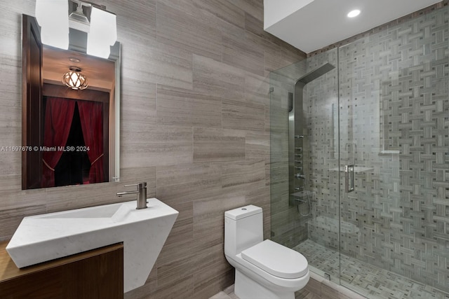 bathroom featuring vanity, toilet, a shower with shower door, and tile walls