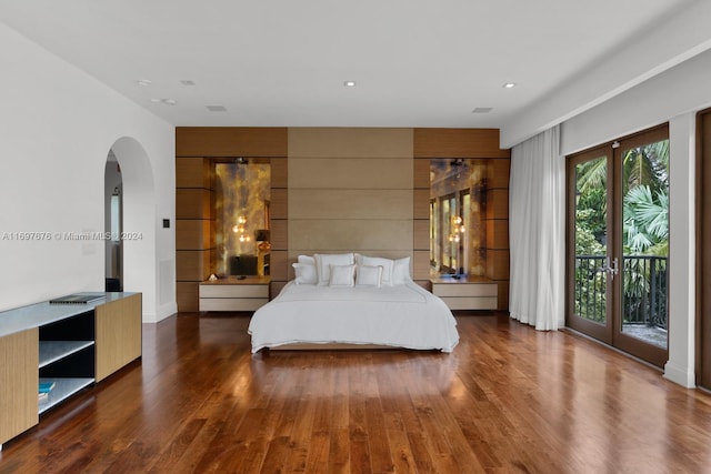 bedroom with dark hardwood / wood-style floors, wood walls, access to outside, and french doors