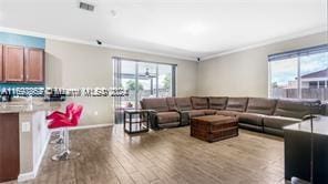 living room with crown molding, plenty of natural light, and wood-type flooring