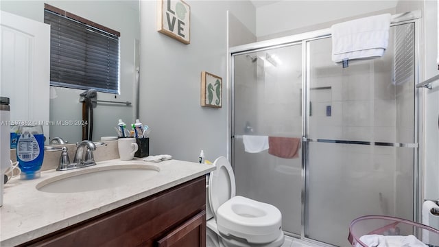 bathroom featuring vanity, a shower with shower door, and toilet