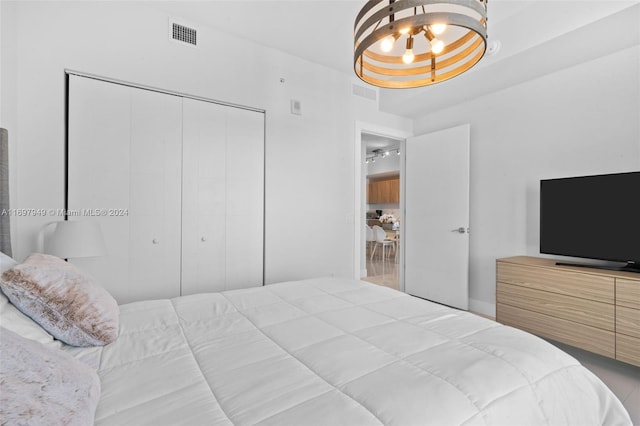 bedroom featuring an inviting chandelier, a tray ceiling, and a closet