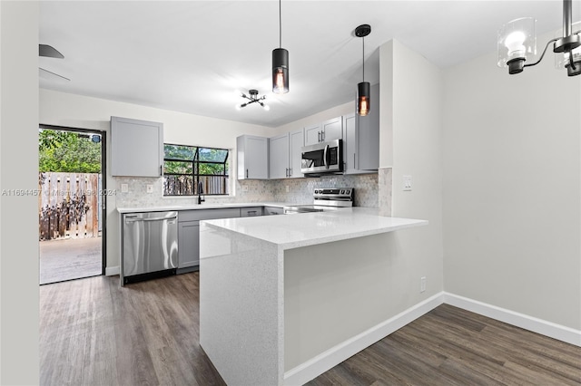 kitchen with kitchen peninsula, stainless steel appliances, gray cabinets, and dark hardwood / wood-style floors