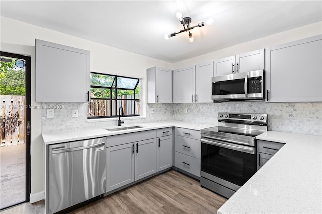 kitchen with appliances with stainless steel finishes, light hardwood / wood-style floors, gray cabinetry, and sink