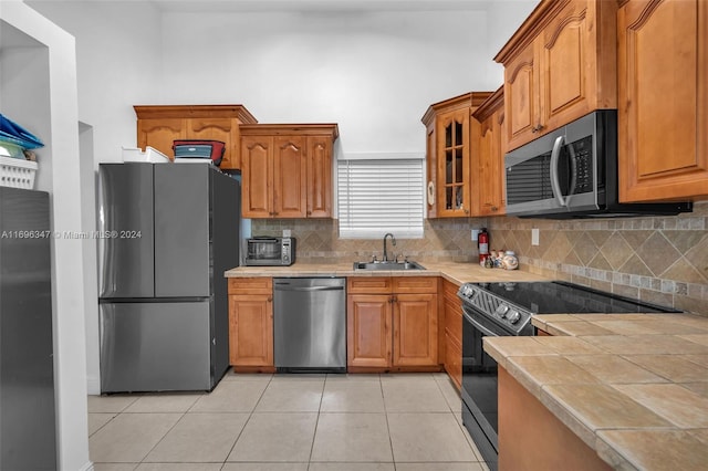 kitchen with backsplash, sink, light tile patterned flooring, and stainless steel appliances