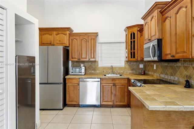 kitchen featuring tile counters, sink, tasteful backsplash, light tile patterned flooring, and appliances with stainless steel finishes