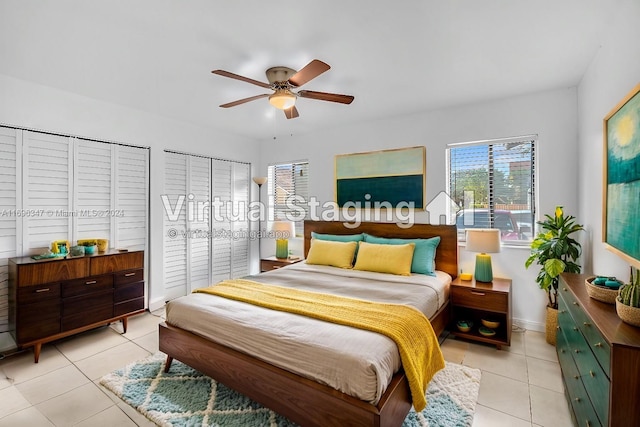 bedroom with ceiling fan, light tile patterned floors, and two closets