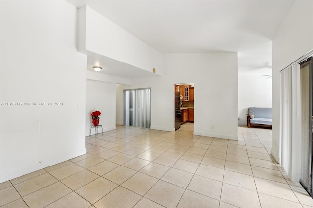 tiled spare room with ceiling fan and a high ceiling