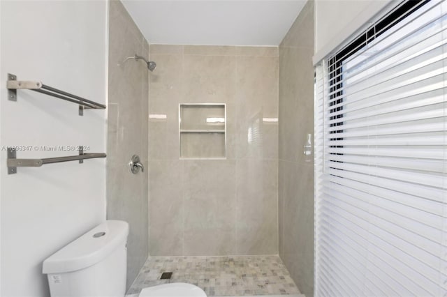 bathroom with a tile shower and toilet