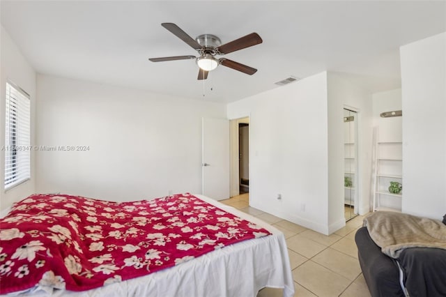 tiled bedroom featuring ensuite bathroom and ceiling fan