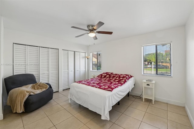 bedroom with light tile patterned floors, two closets, and ceiling fan