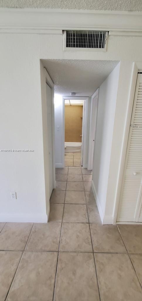 hall with light tile patterned floors and a textured ceiling