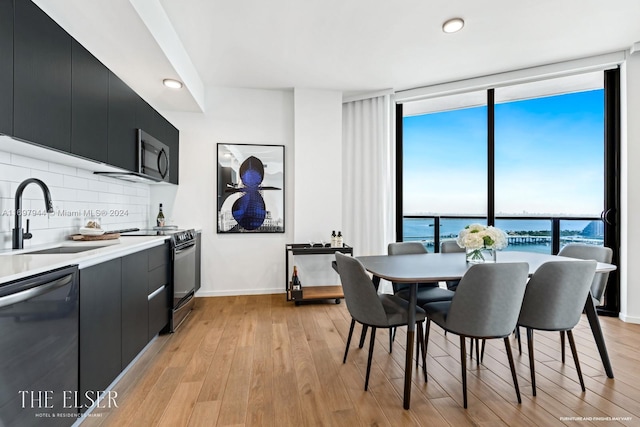 dining room featuring sink, a water view, and light hardwood / wood-style floors