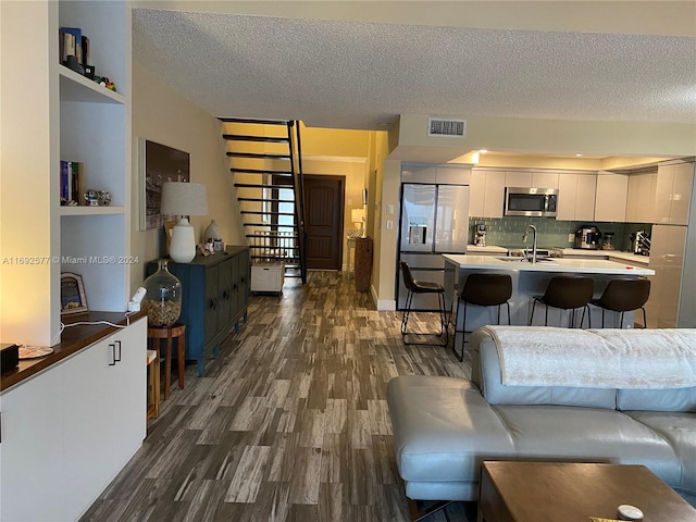 living room featuring a textured ceiling, dark wood-type flooring, and sink