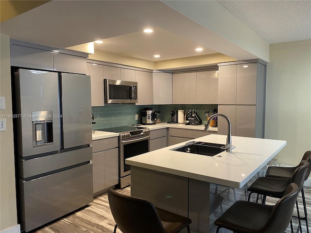 13380 SW 91st Ter Unit E, Miami, FL 33186 - kitchen featuring appliances with stainless steel finishes, gray cabinetry, a breakfast bar area, modern cabinets, and light wood-type flooring