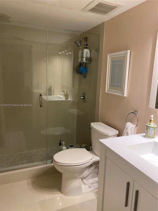 bathroom featuring tile patterned flooring, vanity, toilet, and a shower with door