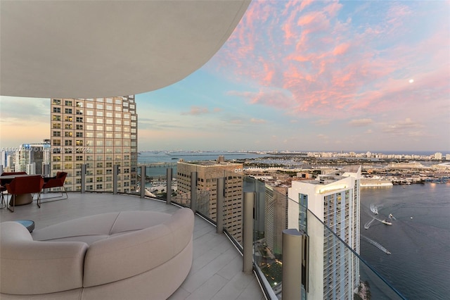 balcony at dusk featuring a water view