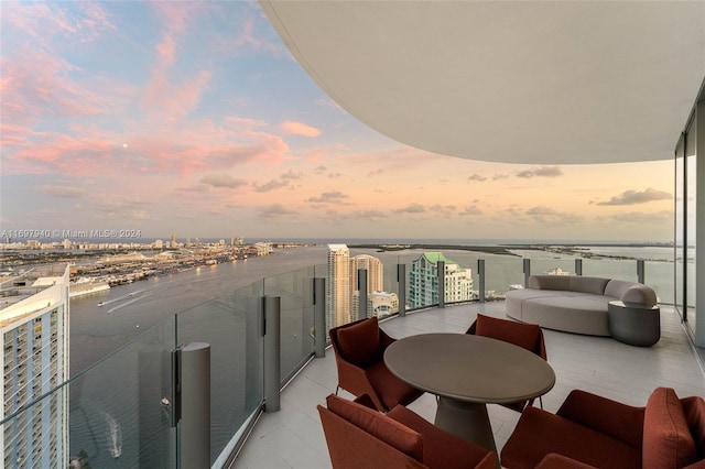 balcony at dusk with outdoor lounge area and a water view