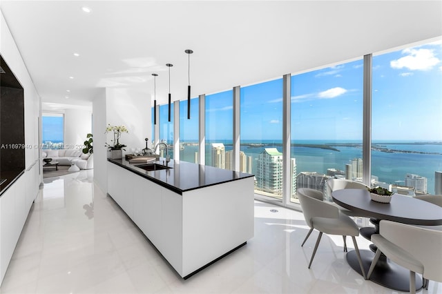 kitchen featuring white cabinetry, sink, a water view, and pendant lighting