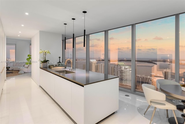 kitchen with a wealth of natural light, white cabinetry, sink, and hanging light fixtures