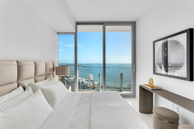 bedroom with a wall of windows, a water view, and multiple windows