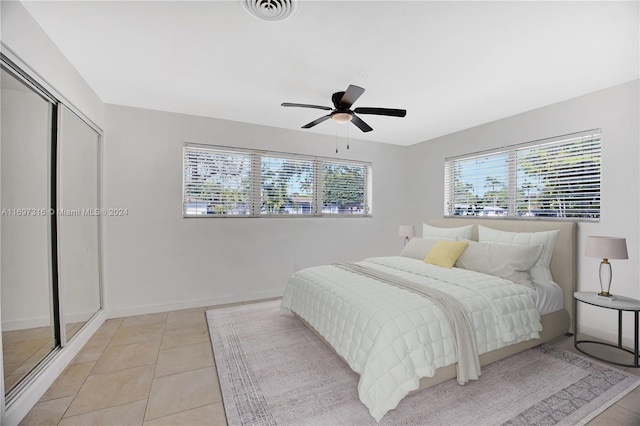 tiled bedroom with ceiling fan and a closet