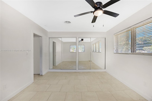 unfurnished bedroom featuring multiple windows, light tile patterned floors, and ceiling fan