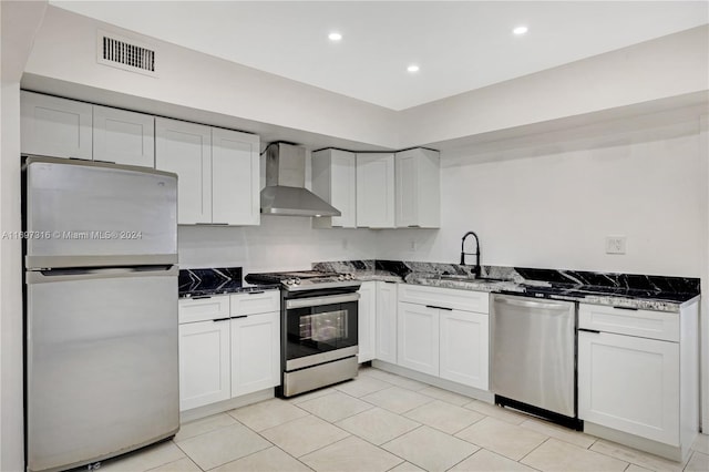 kitchen featuring dark stone countertops, sink, wall chimney range hood, and stainless steel appliances